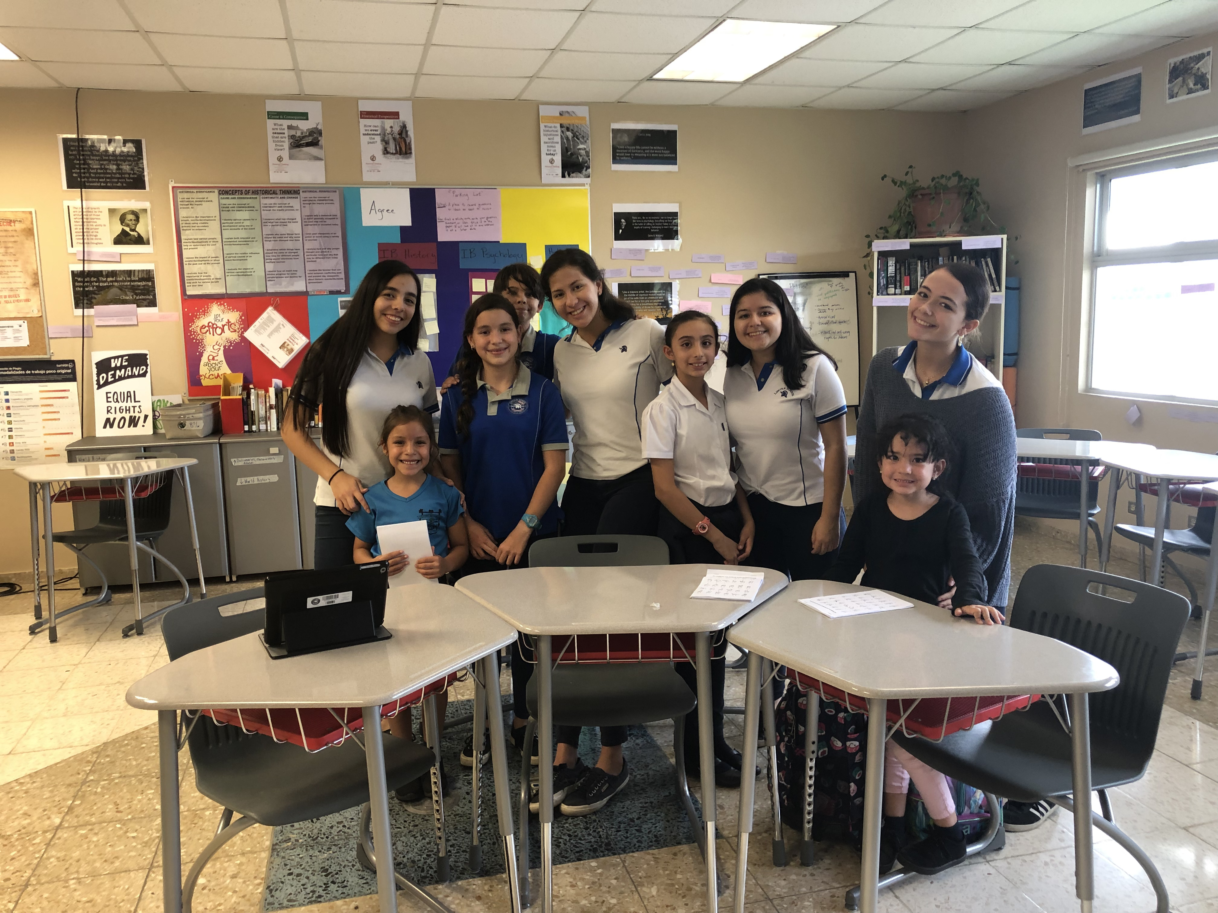 Group of students posing in a classroom with laptops and study materials