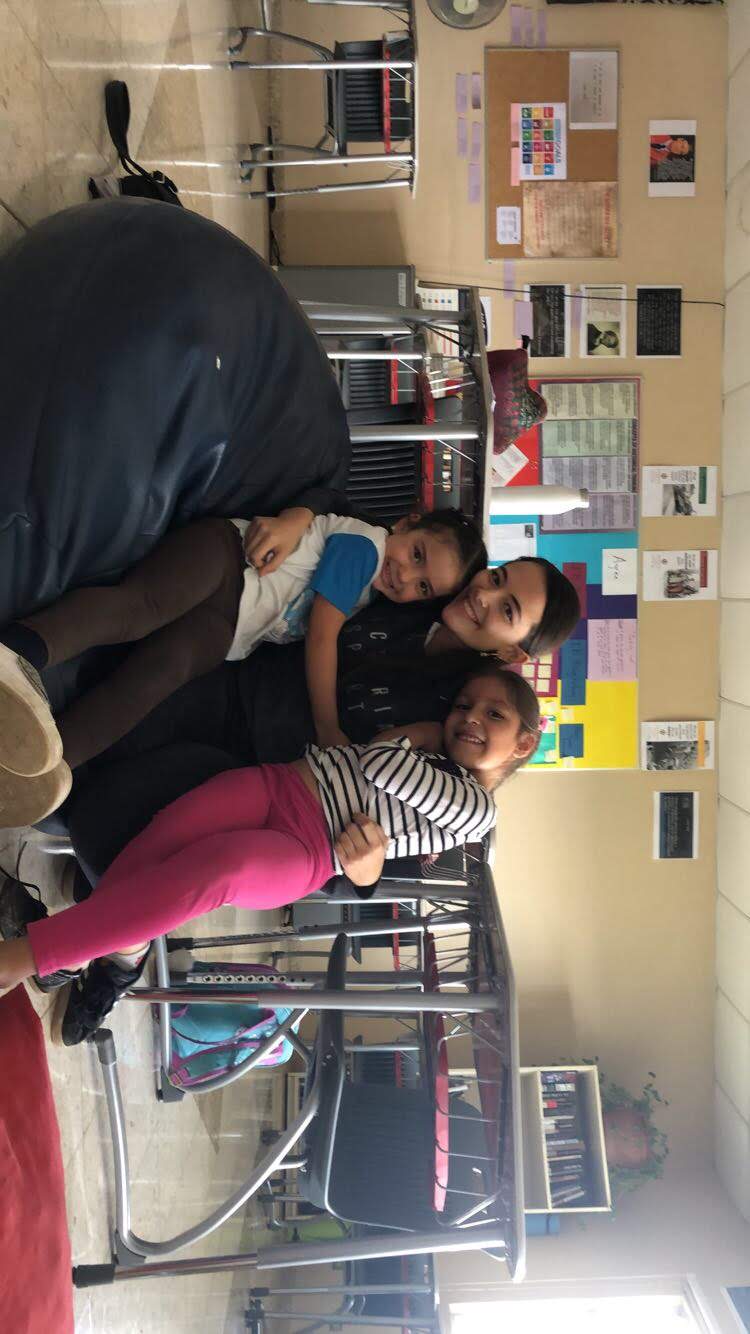Inenglish volunteer teacher smiling with a group of young students in a classroom