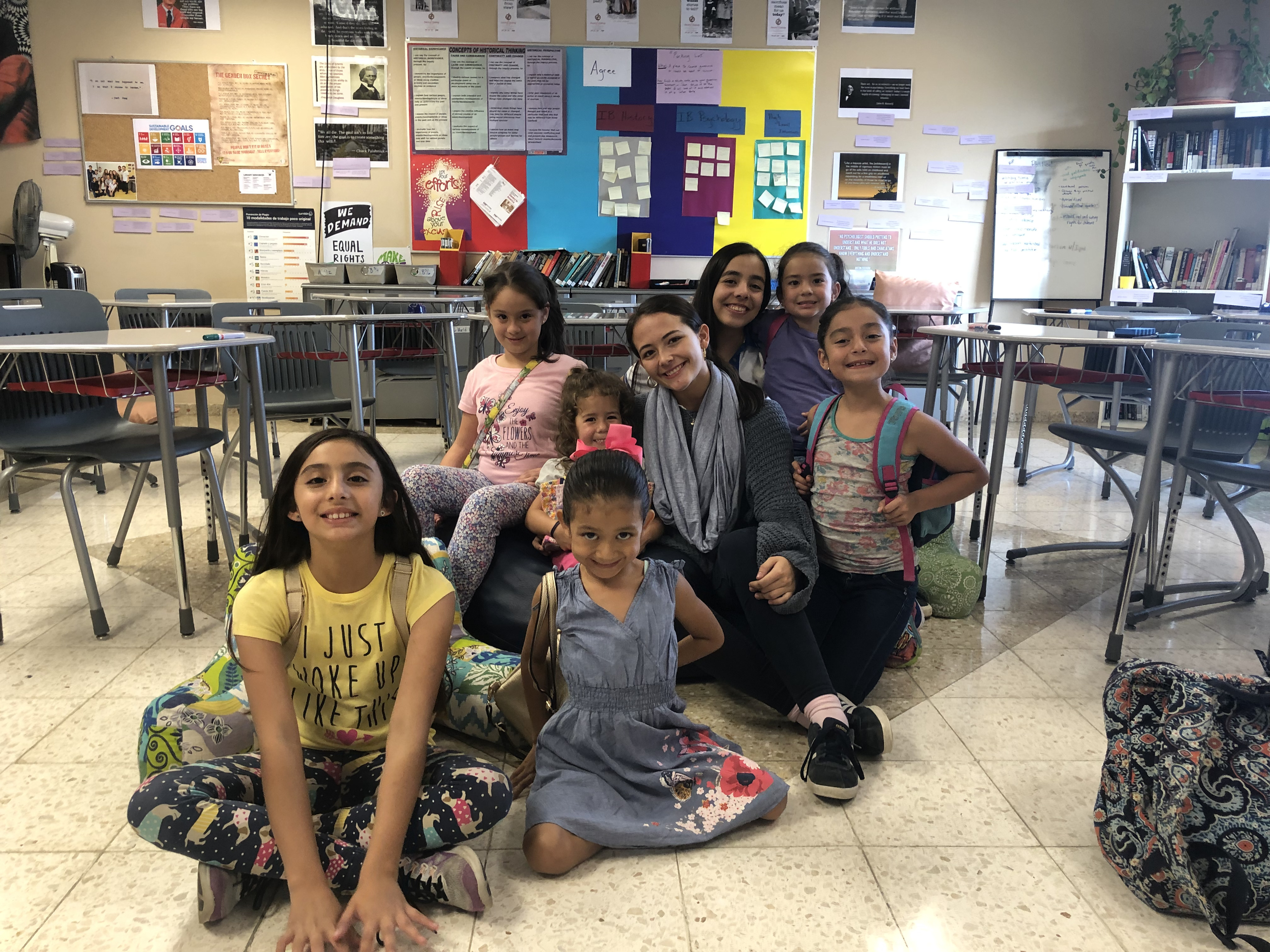 Students smiling together in a classroom decorated with learning posters